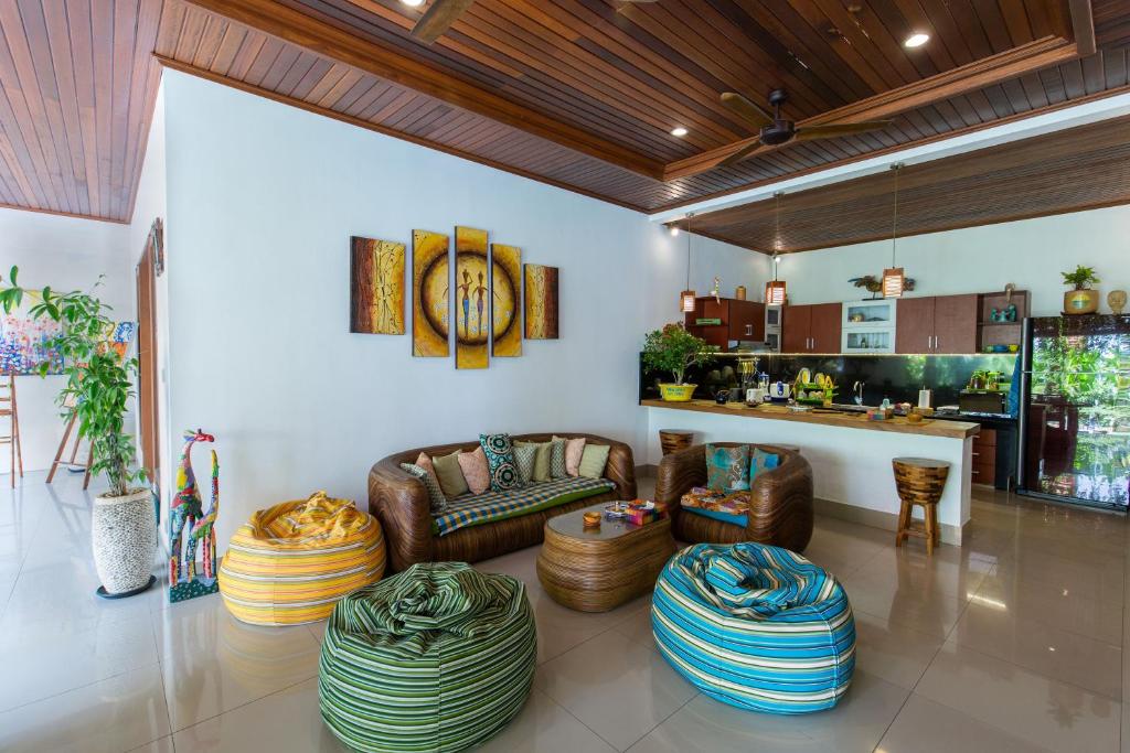 a living room with couches and chairs and a kitchen at MasBro ART Villas in Seminyak