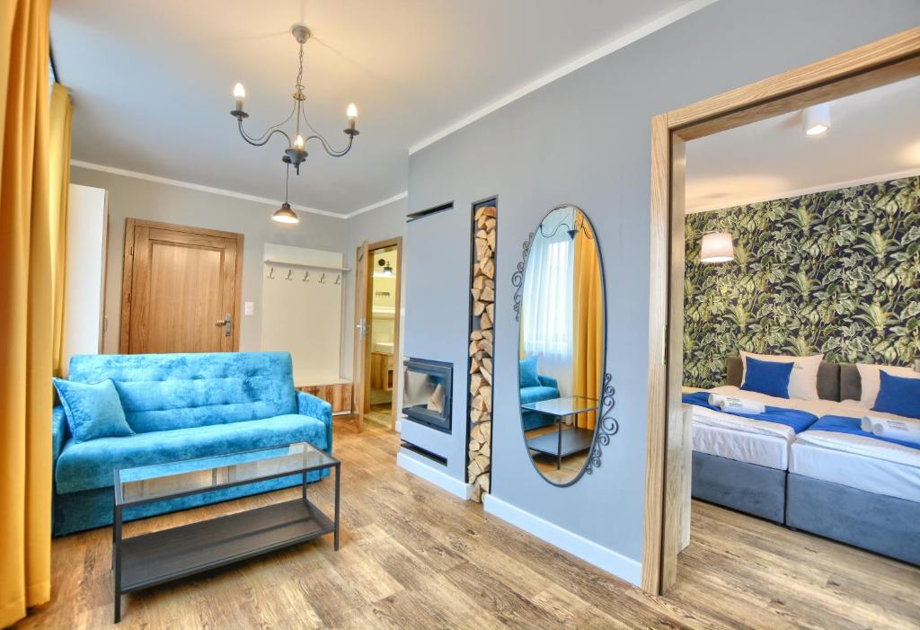 a living room with a blue couch and a mirror at APARTAMENTY SPA & RESORT BUKOWIEC in Polańczyk