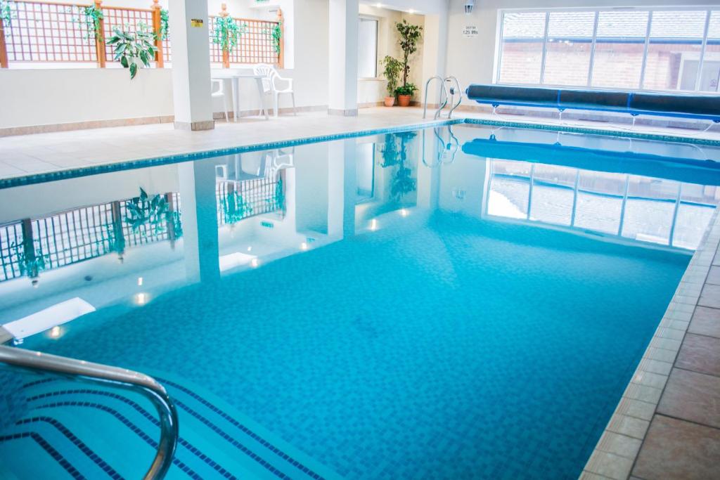 a swimming pool with blue water in a building at Beachlands Hotel in Weston-super-Mare