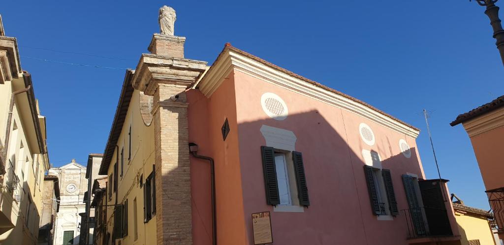 un edificio rosa con una estatua encima en La Piazza, en Cantalupo in Sabina