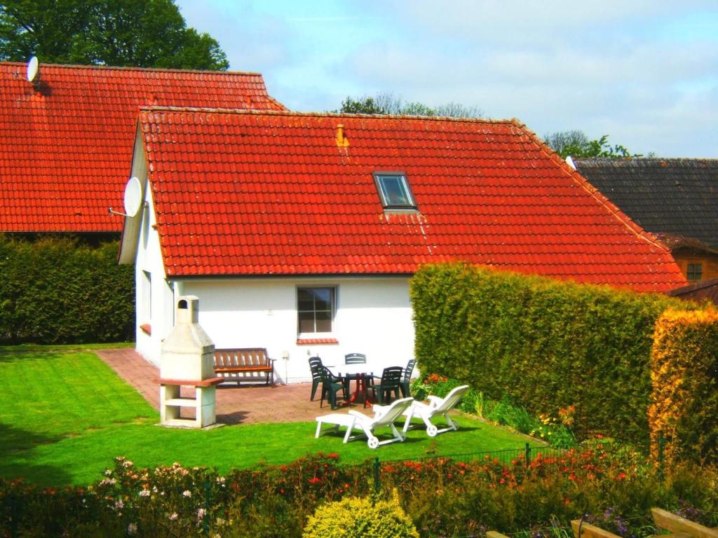 a white house with a red roof and a table and chairs at Ferienhaus Sonnenschein Heyken in Werdum