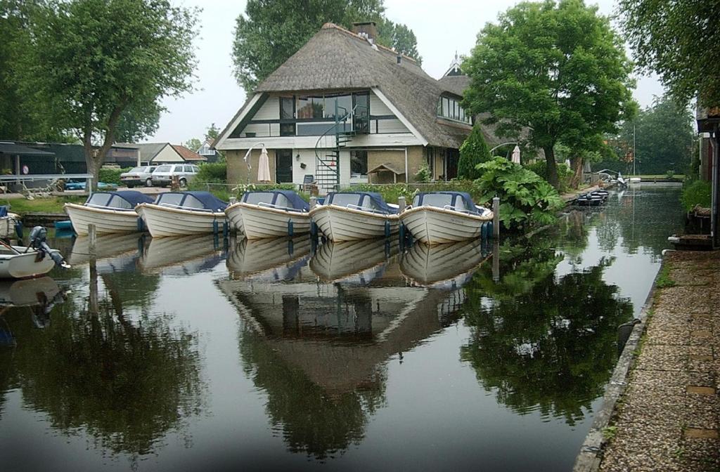 um grupo de barcos estacionados na água em frente a uma casa em De Mariahoeve em Terherne