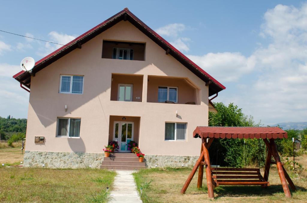 une maison avec un banc devant dans l'établissement Pensiunea Aly, à Bumbesti Pitic
