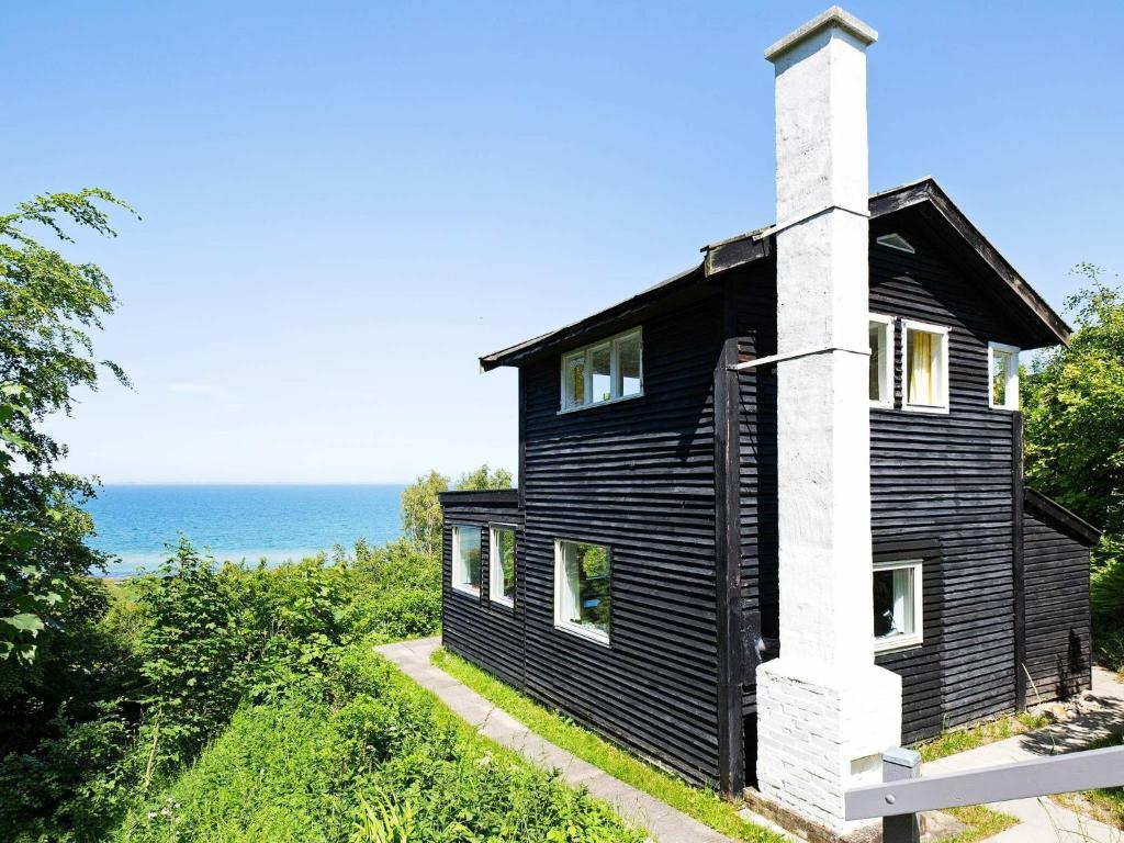 Asnæsにある4 person holiday home in Asn sの白煙突と海の黒い家