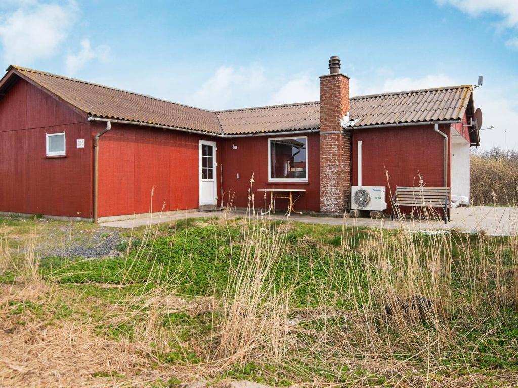 une maison rouge avec une porte blanche dans un champ dans l'établissement 6 person holiday home in R m, à Lakolk