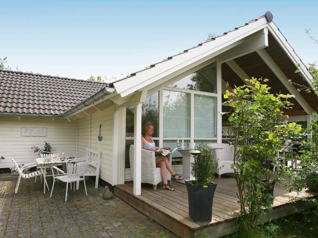 a woman sitting on the porch of a house at 6 person holiday home in Dronningm lle in Gilleleje