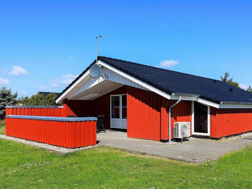 a red house with a fence in front of it at 8 person holiday home in Vejers Strand in Vejers Strand