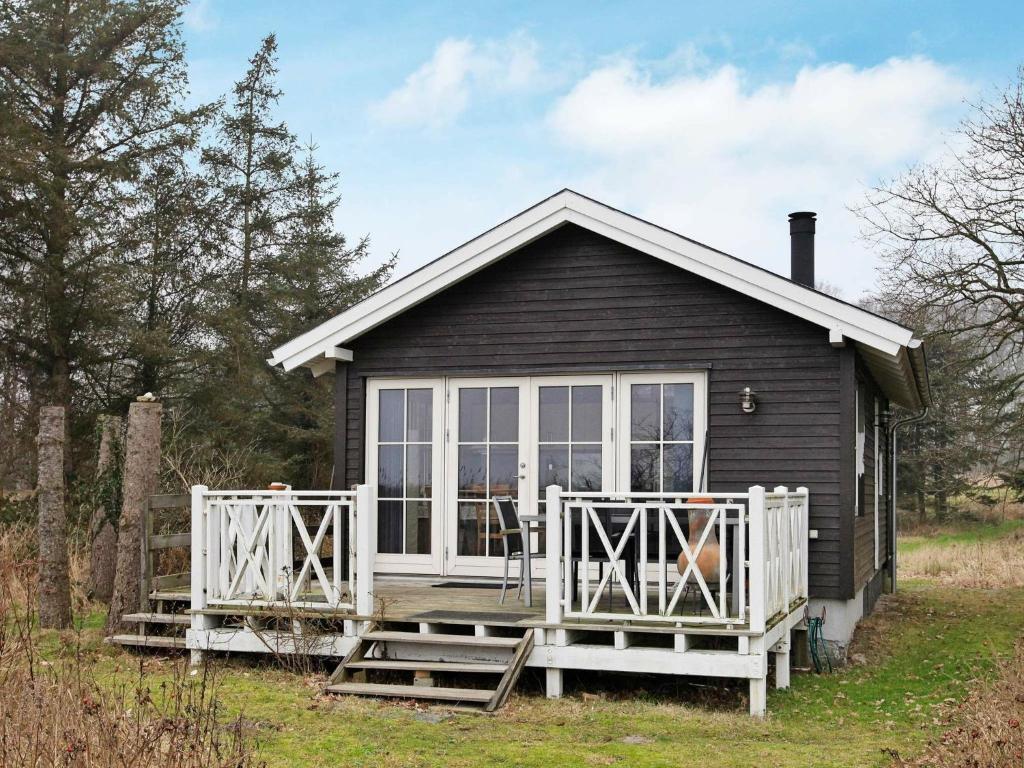 een klein zwart huis met een groot raam en een veranda bij 4 person holiday home in Oure in Oure