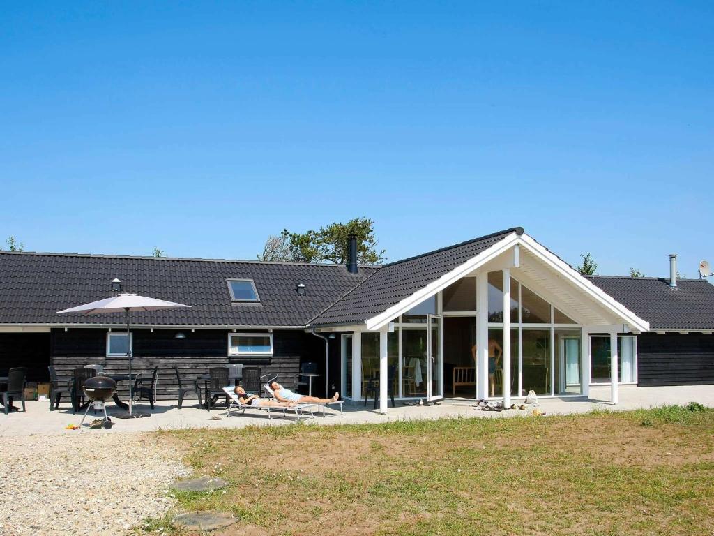 a house with people sitting on the patio of it at 14 person holiday home in H jslev in Sundstrup