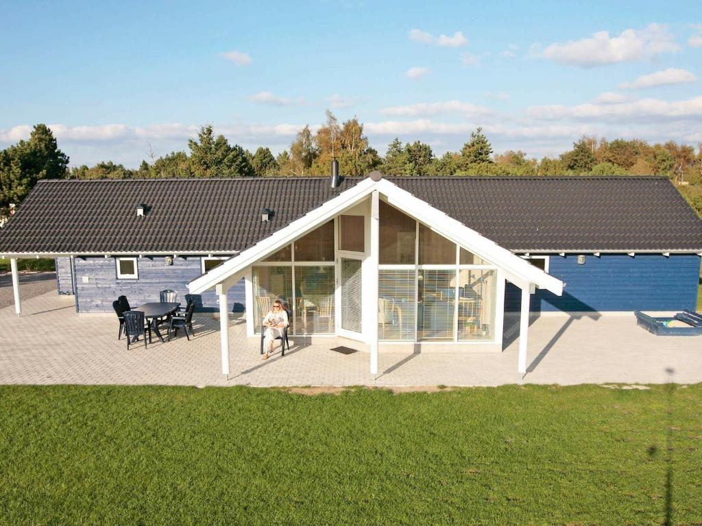 a house with a conservatory with a woman sitting in a chair at 10 person holiday home in R dby in Kramnitse