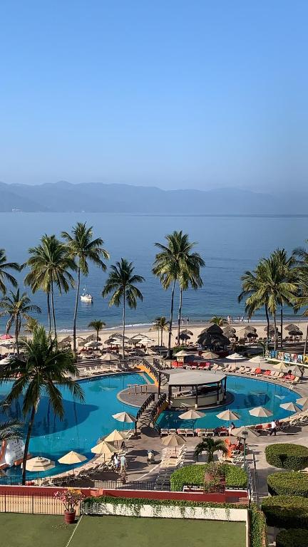 a resort with a pool and palm trees and the beach at Torre Condomar Beside Sunscape in Puerto Vallarta