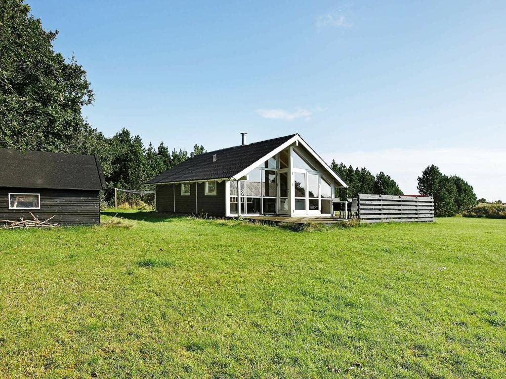 una pequeña casa en un campo al lado de un edificio en 6 person holiday home in Snedsted en Stenbjerg