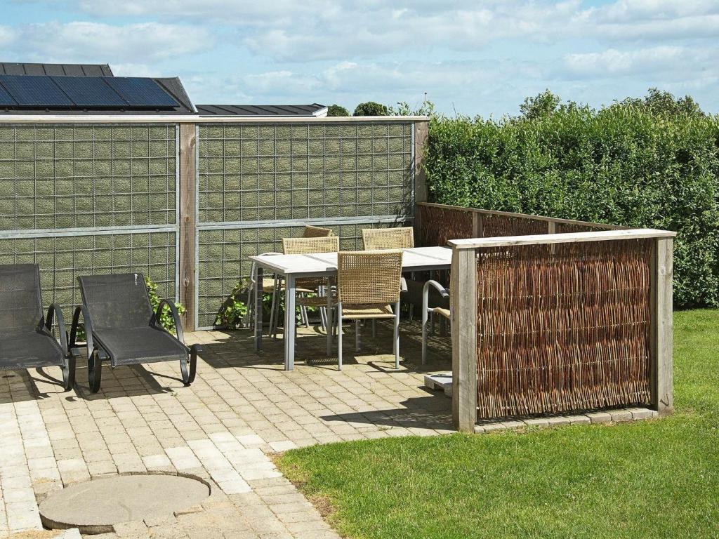 een patio met een tafel en stoelen en een hek bij 6 person holiday home in Hejls in Hejls