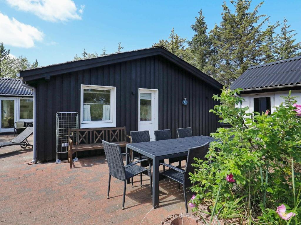 una casa negra con una mesa y sillas en un patio en 6 person holiday home in lb k en Ålbæk