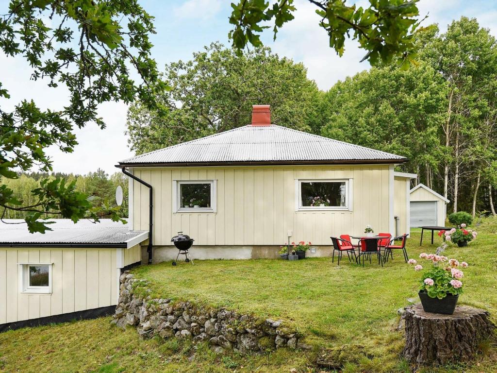 a white house with a table and chairs in the yard at 5 person holiday home in BULLAREN in Stabäckehult