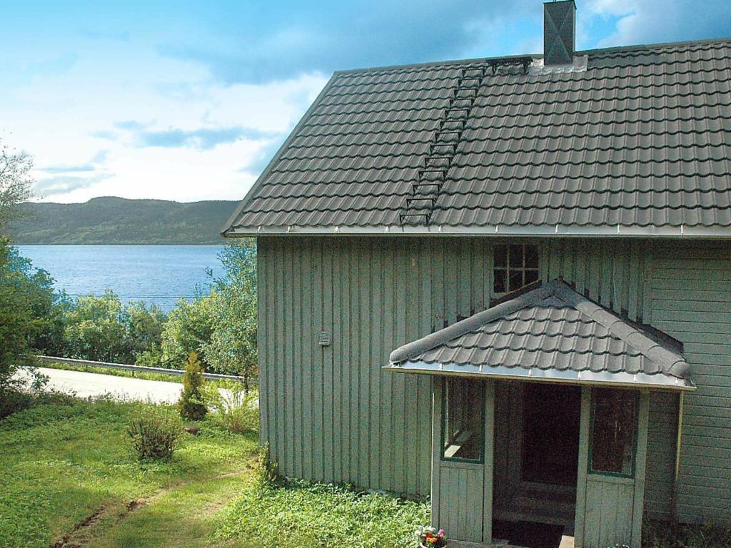 una antigua casa verde con vistas al agua en Four-Bedroom Holiday home in Åfarnes, en Årset