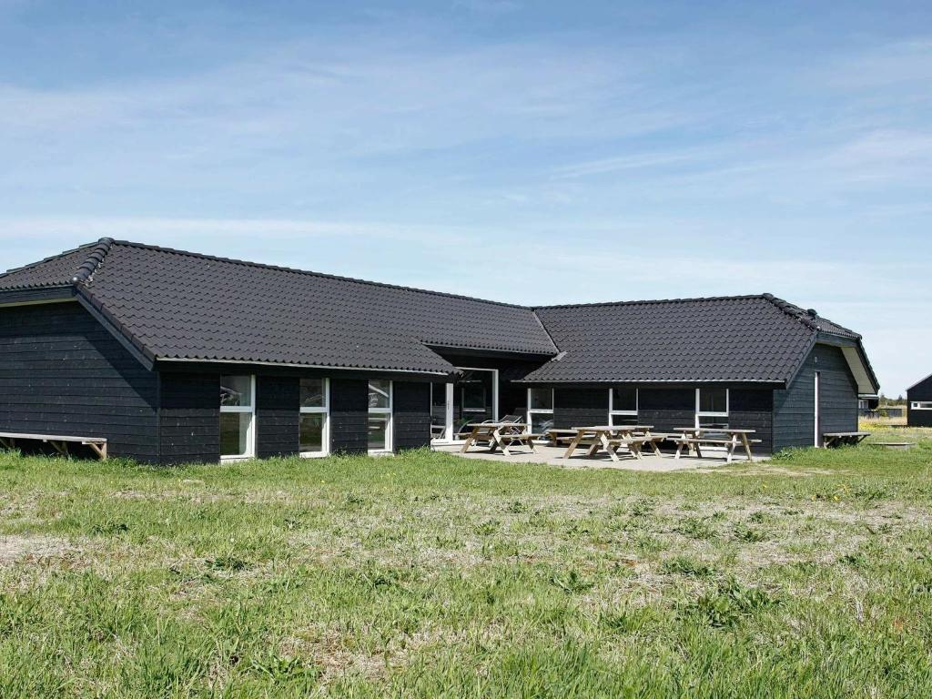un edificio negro con mesas de picnic delante en Ten-Bedroom Holiday home in Brovst, en Brovst