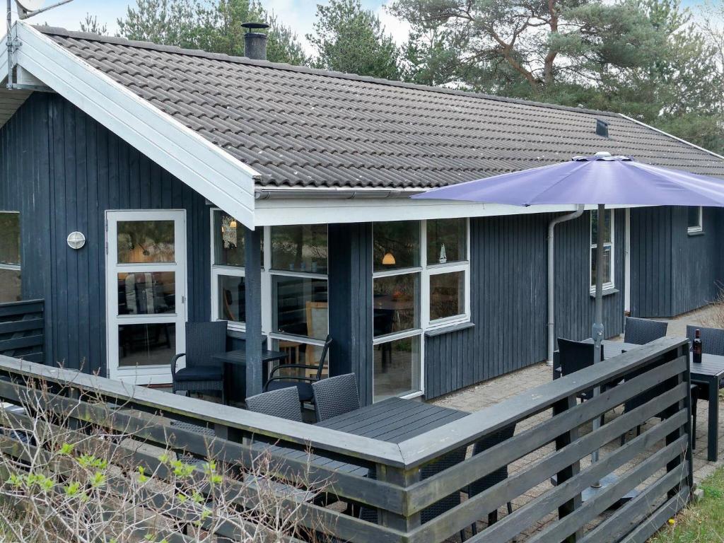 a blue house with a deck with an umbrella at 6 person holiday home in Fjerritslev in Torup Strand
