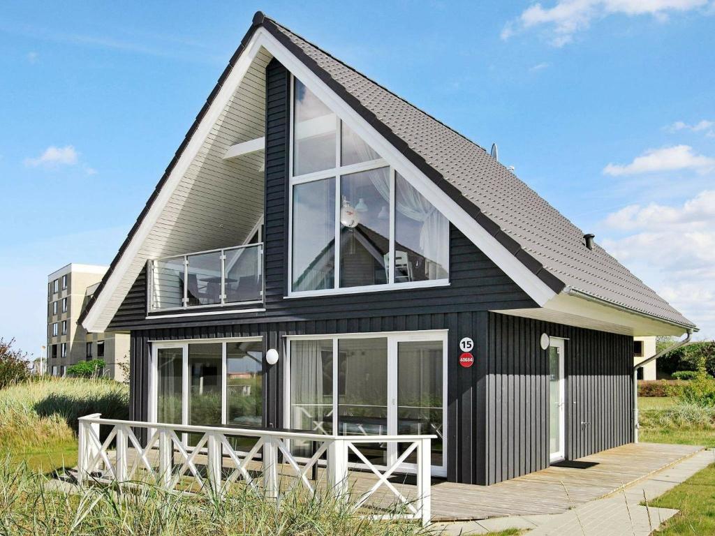 6 person holiday home in Wendtorf في Wendtorf: منزل أسود مع نوافذ كبيرة وشرفة