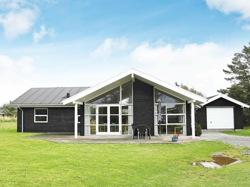 ein schwarzes Haus mit einer weißen Garage in der Unterkunft 8 person holiday home in Hjørring-By Traum in Vester Vidstrup