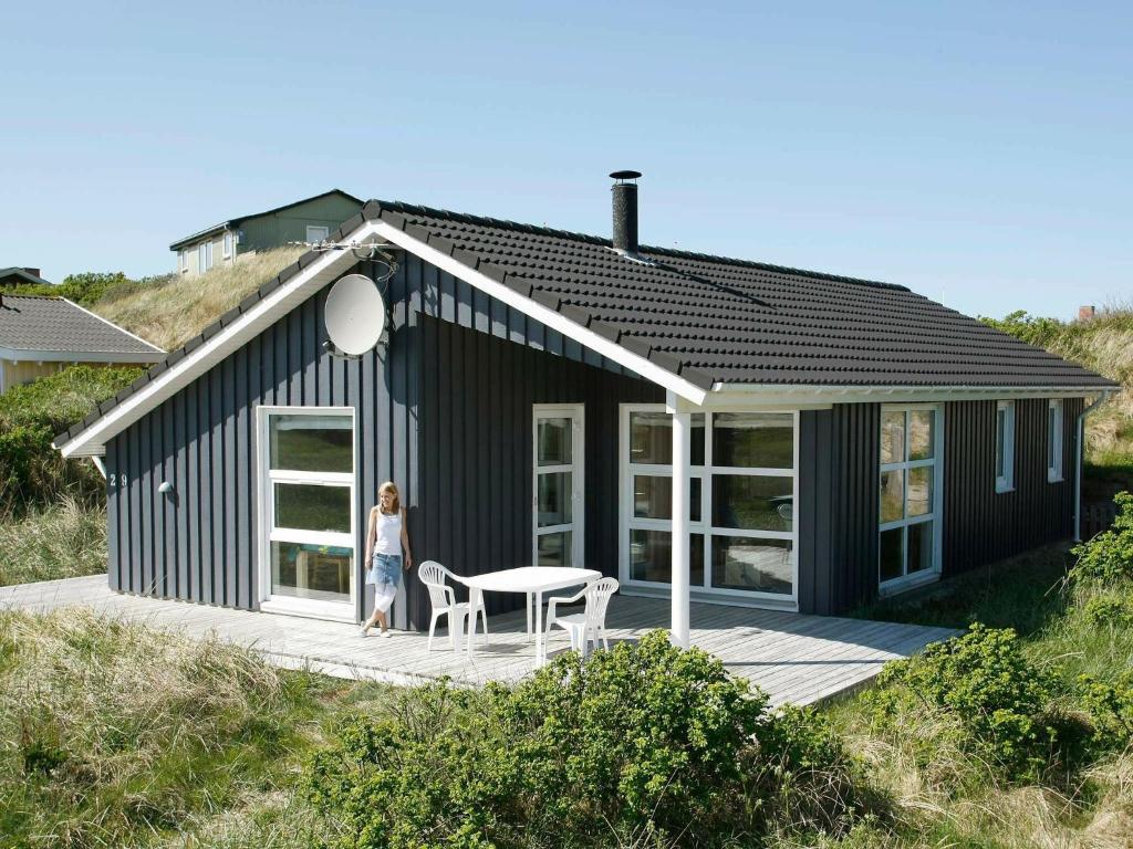 een vrouw die voor een zwart huis staat bij 5 person holiday home in L kken in Løkken