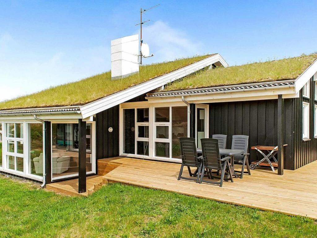 una casa con techo de hierba con sillas en una terraza en 8 person holiday home in Saltum, en Saltum