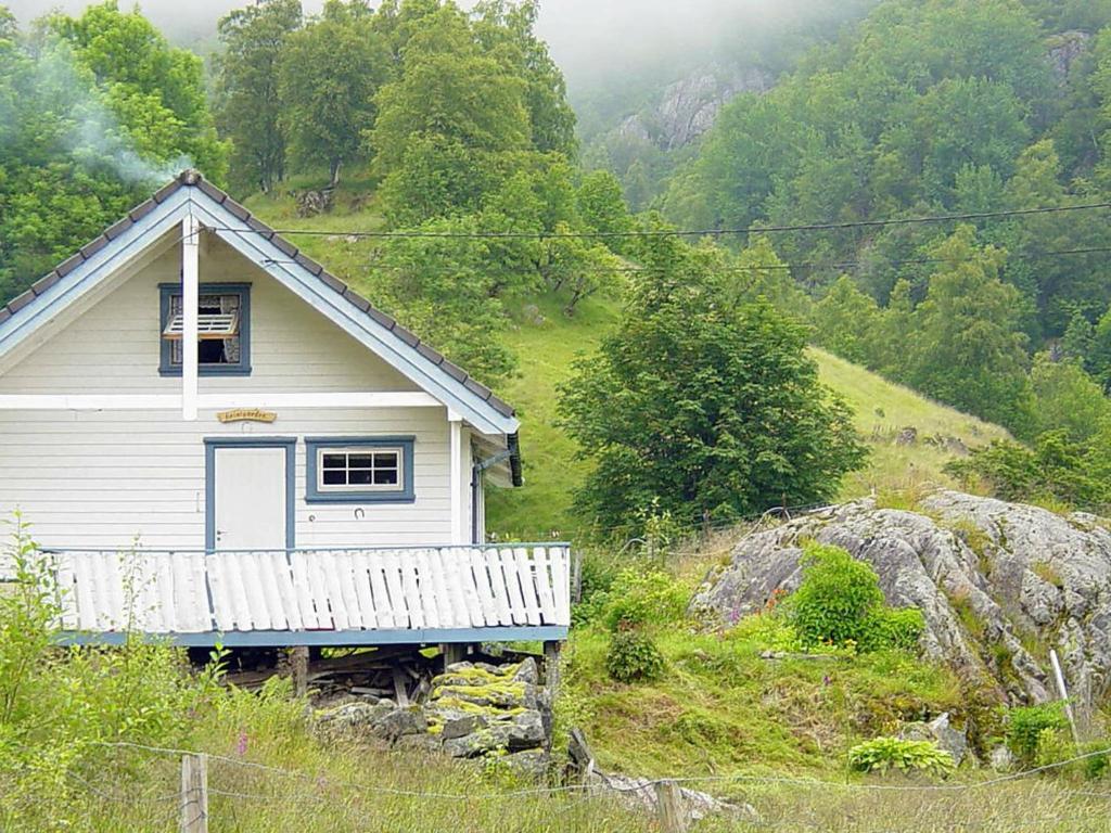 Kyrping的住宿－Three-Bedroom Holiday home in Åkra，一座小白房子,位于山丘上,树木繁茂