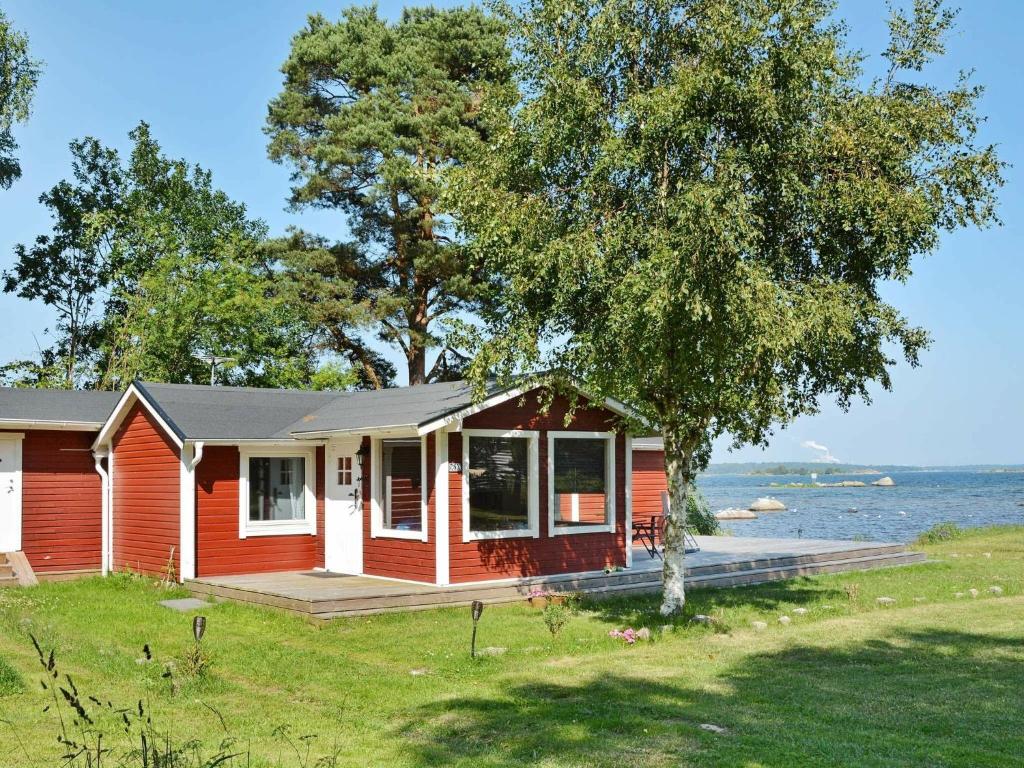 una pequeña casa roja con un porche y un árbol en 2 person holiday home in SÖLVESBORG-By Traum, en Björkenäs