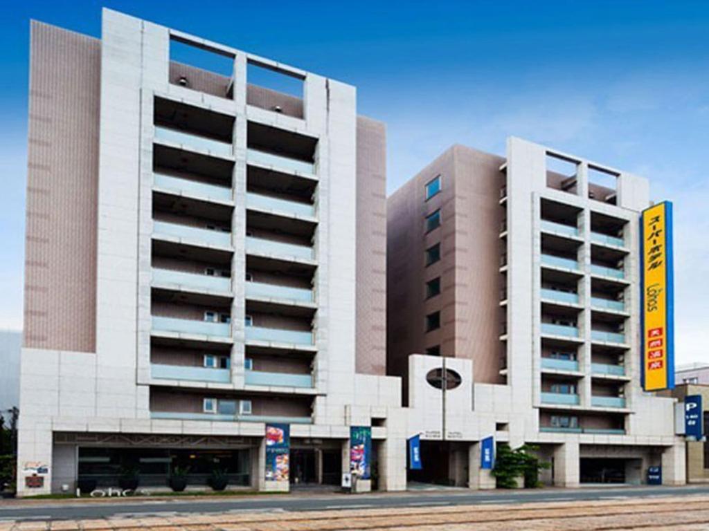 twee hoge gebouwen voor een parkeerplaats bij Super Hotel Lohas Kumamoto Natural Hot Springs in Kumamoto