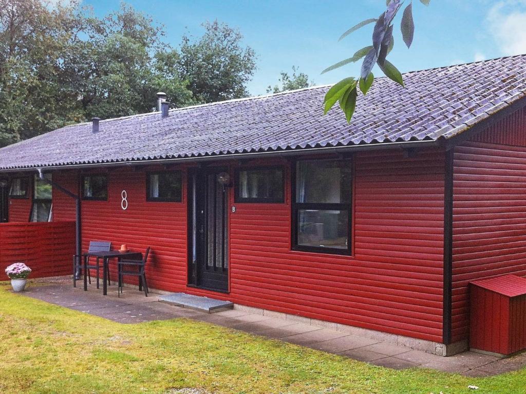 a red house with a table in a yard at 5 person holiday home in Silkeborg in Silkeborg