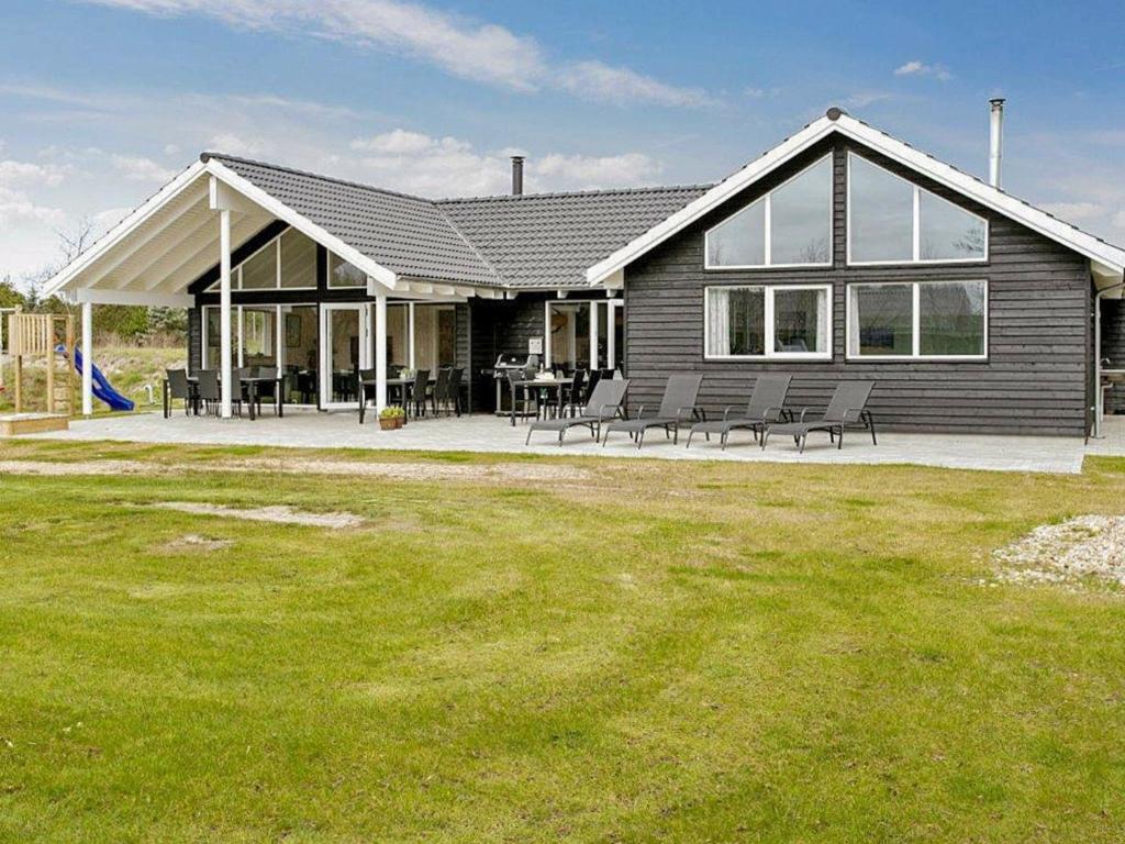 une grande maison avec une terrasse et une pelouse dans l'établissement 18 person holiday home in Bl vand, à Blåvand