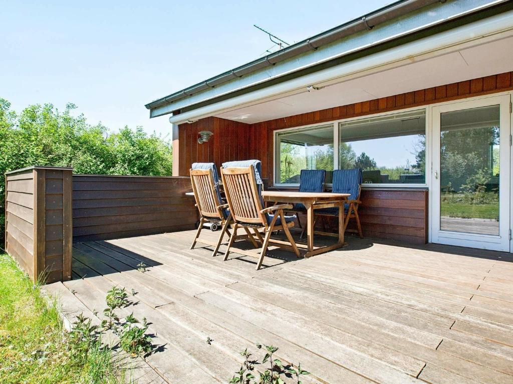 a wooden deck with chairs and a table on a house at Two-Bedroom Holiday home in Ringkøbing 10 in Dannemare