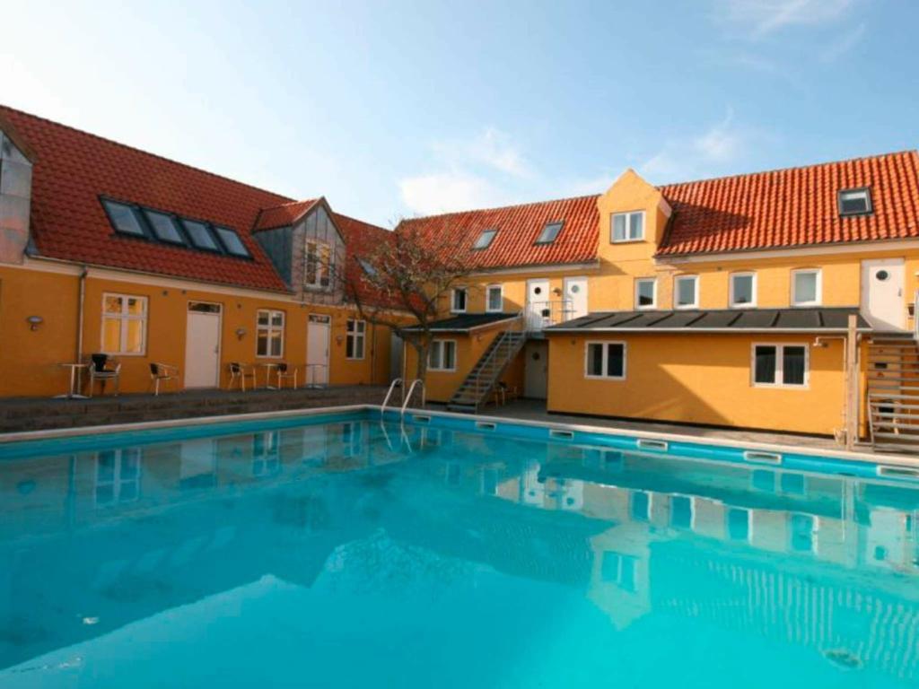 a large swimming pool in front of some buildings at 6 person holiday home in Gudhjem in Gudhjem