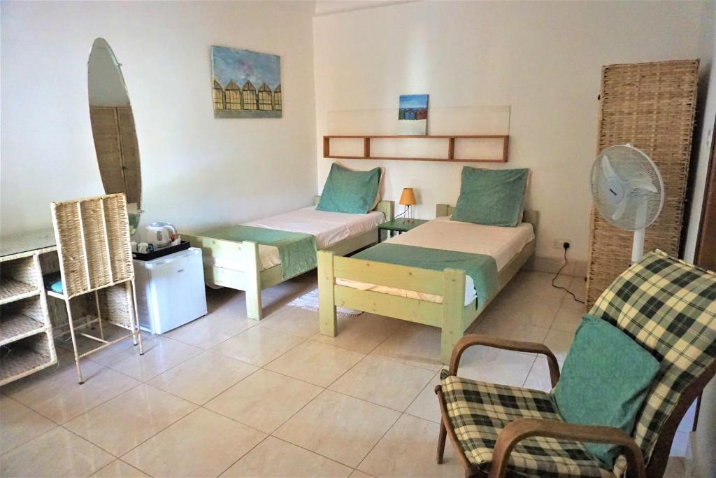 um quarto com duas camas e um sofá e uma cadeira em B & B Villa Calliandra em Bijilo