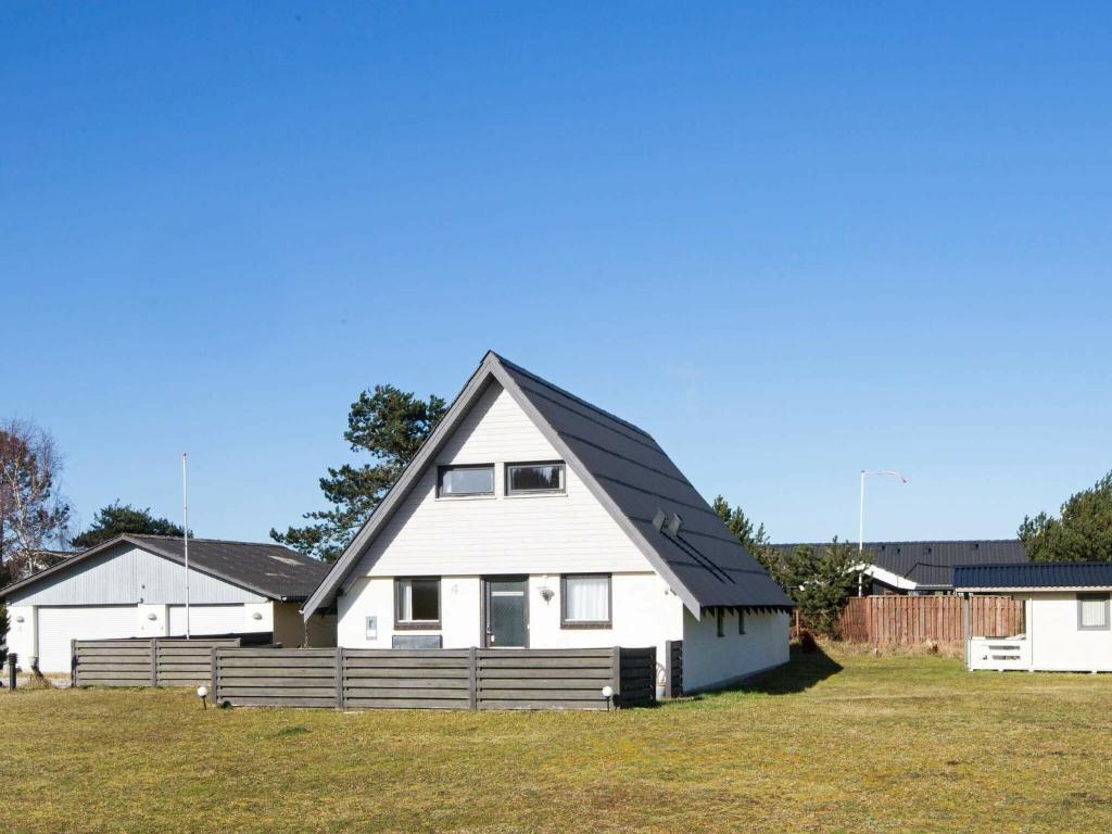 a white house with a black roof on a field at 8 person holiday home in Glesborg in Fjellerup