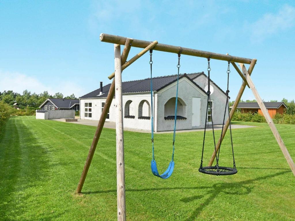a swing set in a yard with a house at 6 person holiday home in Hemmet in Hemmet