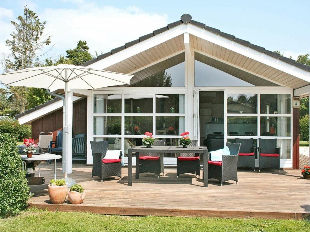 um pavilhão com uma mesa e cadeiras e um guarda-sol em 6 person holiday home in Dannemare em Dannemare