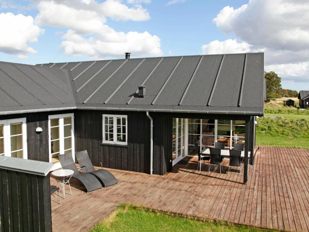 a house with a black roof and a wooden deck at 8 person holiday home in Nysted in Nysted