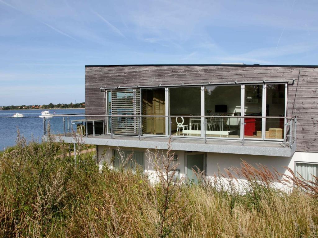 a house with a balcony and a view of the water at 7 person holiday home in Stege in Stege