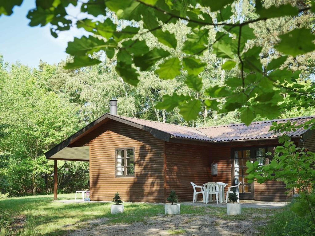 una cabaña de madera con una mesa y sillas frente a ella en Three-Bedroom Holiday home in Rønne 4 en Rønne