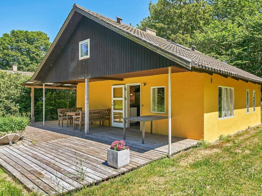 uma pequena casa amarela com um deque de madeira em 6 person holiday home in Aakirkeby em Åkirkeby
