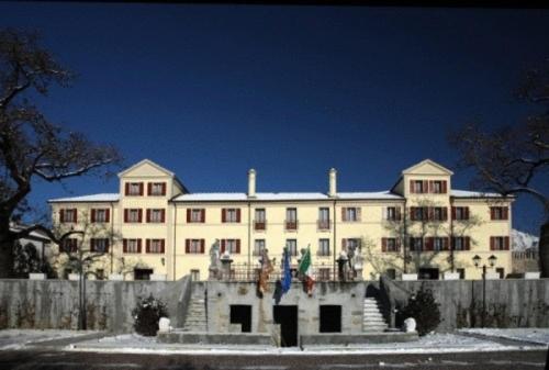 un grand bâtiment blanc avec une clôture devant lui dans l'établissement Park Hotel Villa Carpenada, à Belluno