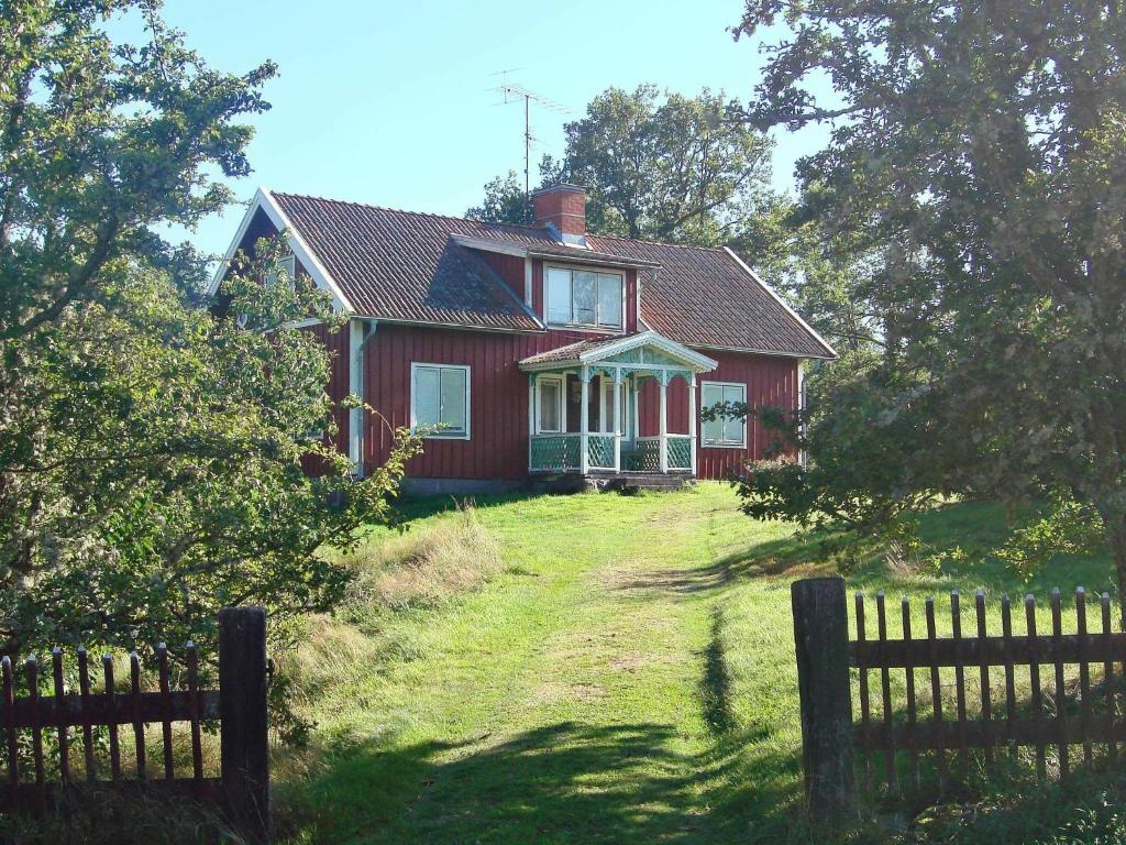 czerwony dom z płotem przed nim w obiekcie 6 person holiday home in M RLUNDA w mieście Fågelfors