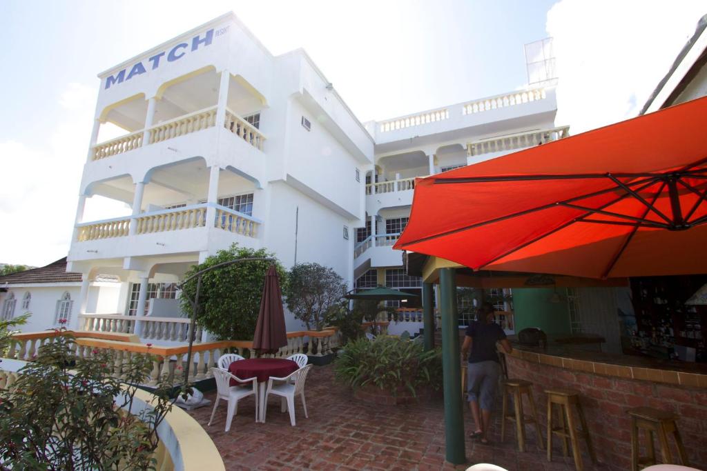 un hotel con sombrilla roja, mesas y sillas en Match Resort, en Port Antonio