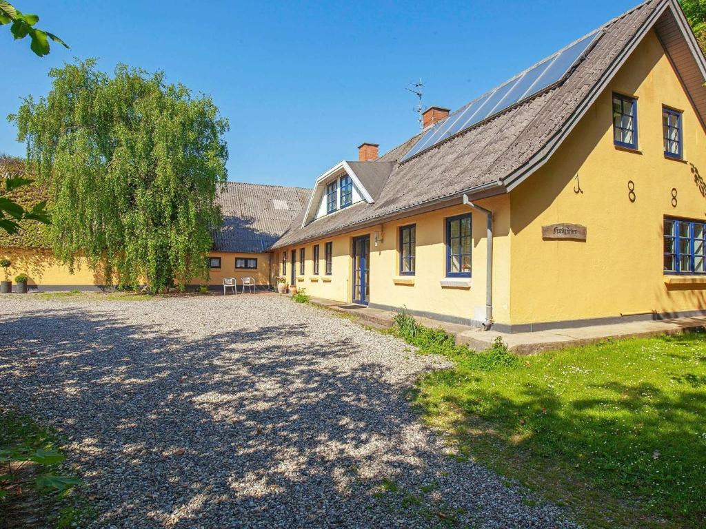 a yellow house with a large driveway in front of it at Cozy Holiday Home in Thyholm with Swimming Pool in Thyholm