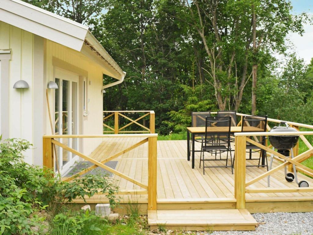 eine Holzterrasse mit einem Tisch und Stühlen auf einem Haus in der Unterkunft One-Bedroom Holiday home in Kållekärr in Apelgården