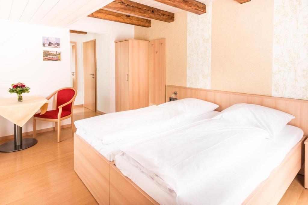 Bett in einem Zimmer mit einem Tisch und einem Stuhl in der Unterkunft Gasthof zum Lamm in Gomadingen
