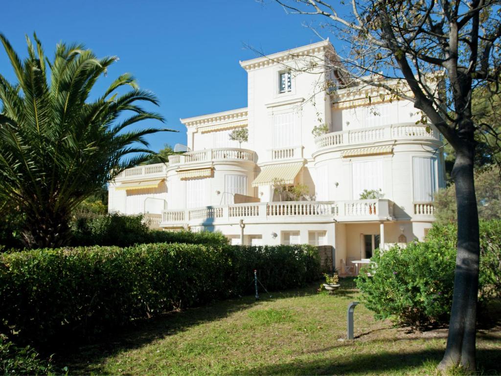 a large white building with a palm tree at Apartment in villa with pool and beach access in Saint-Raphaël