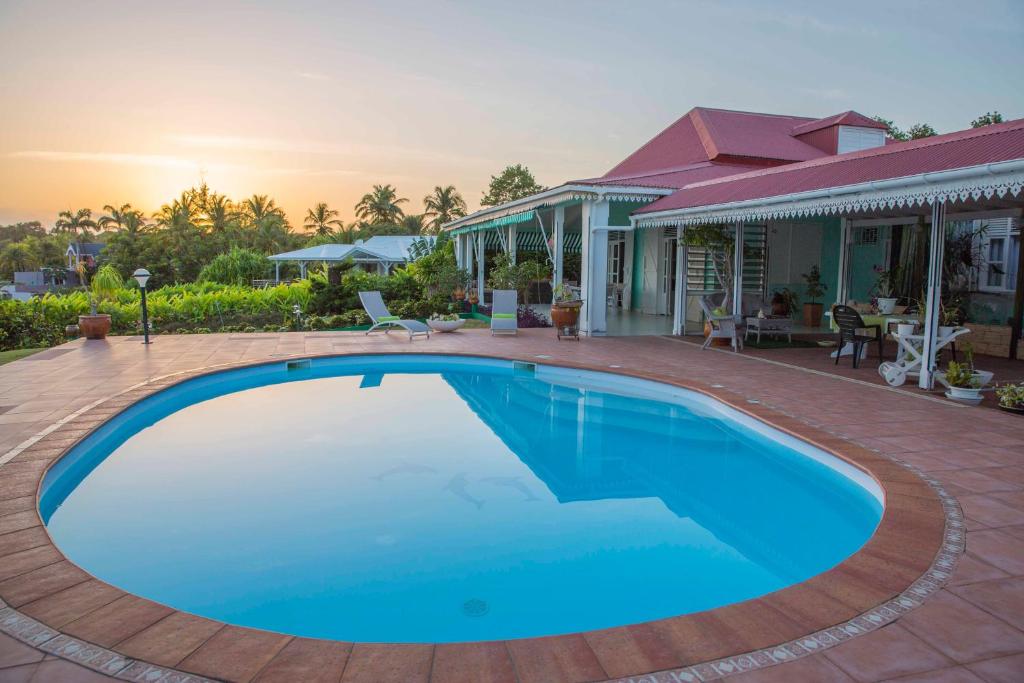 a large blue swimming pool in front of a house at Villa Joland in Sainte-Anne