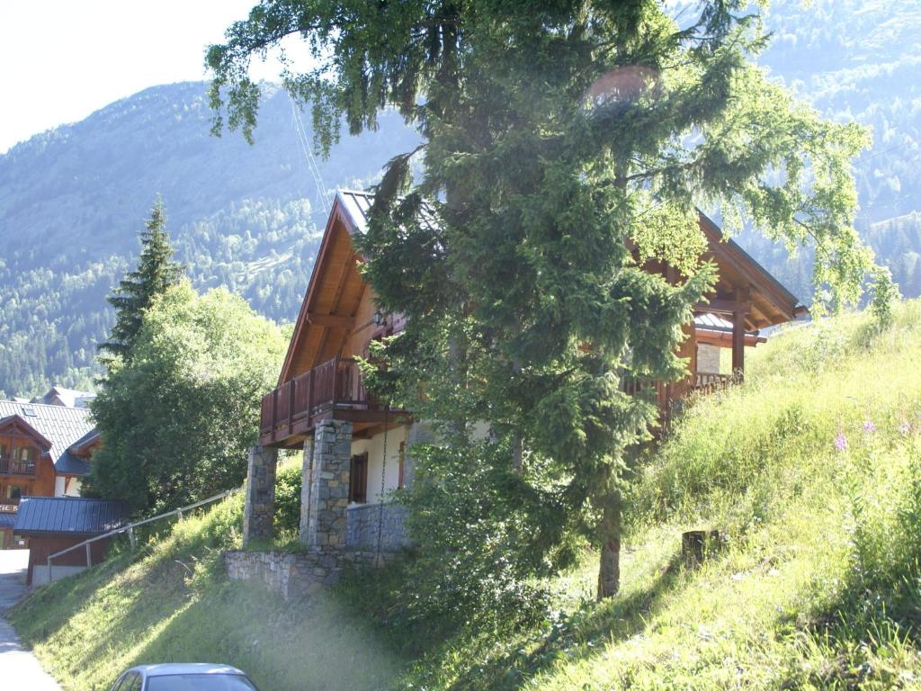 Mountain Chalet in Oz en Oisans with Lovely Views over Lake في Oz: منزل على جانب تل مع شجرة